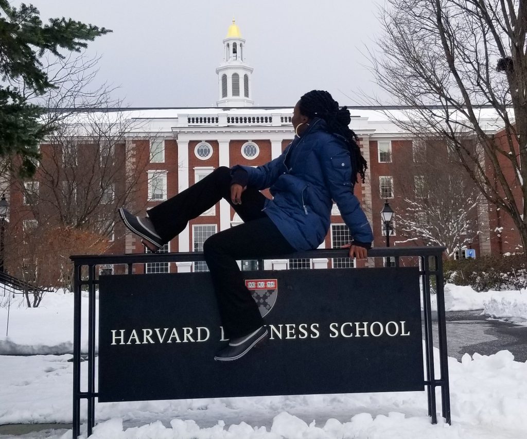 Woman sitting on Harvard Business School sign